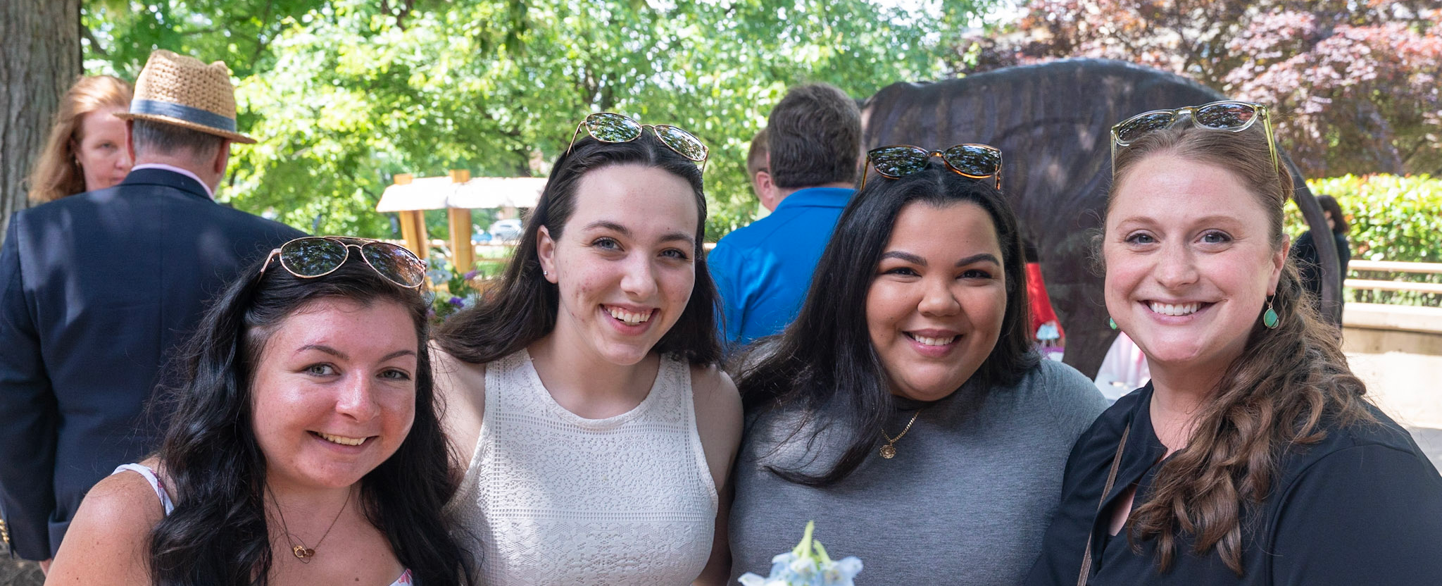 Four smiling students stand together outside of the Campus Center