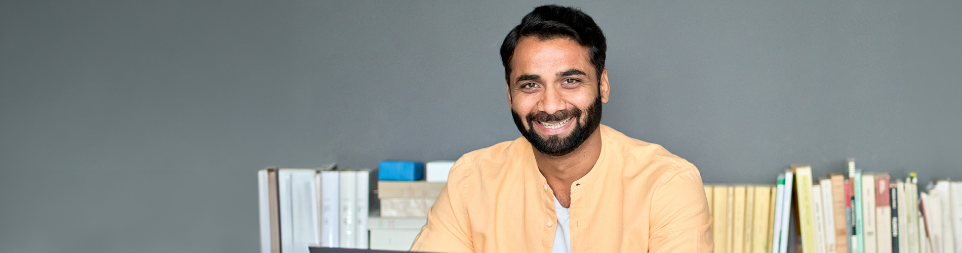 Business school student sitting at table with books in the background