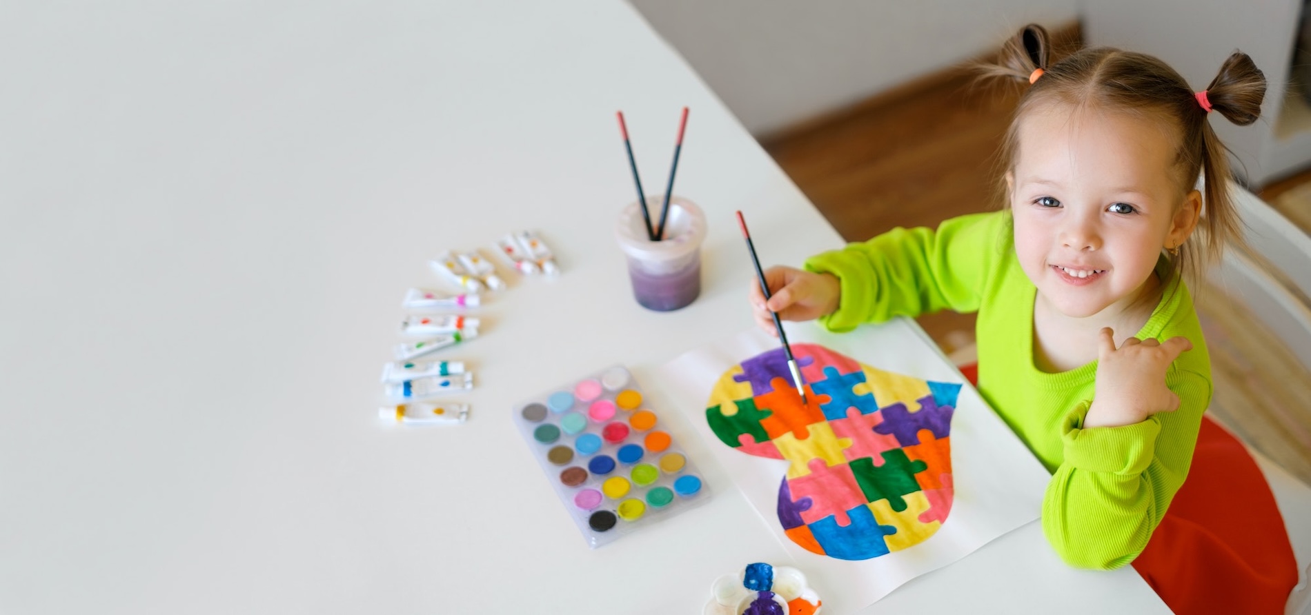 A pre-school aged child painting and smiling