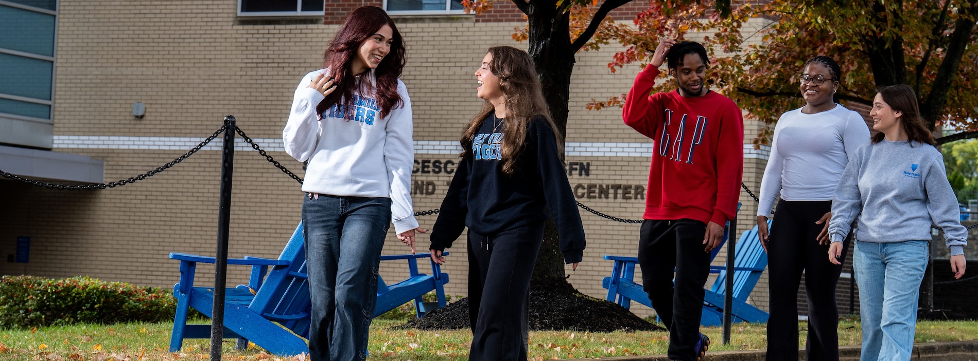 Five students walking through campus on an autumn day
