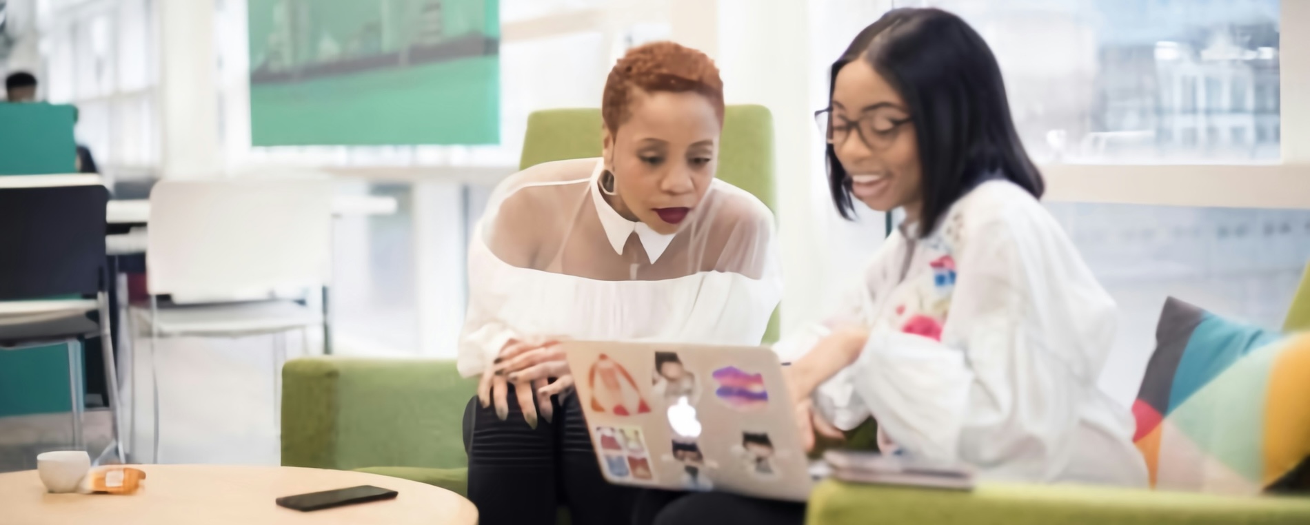 An intern and a mentor in a conference room, talking around a laptop