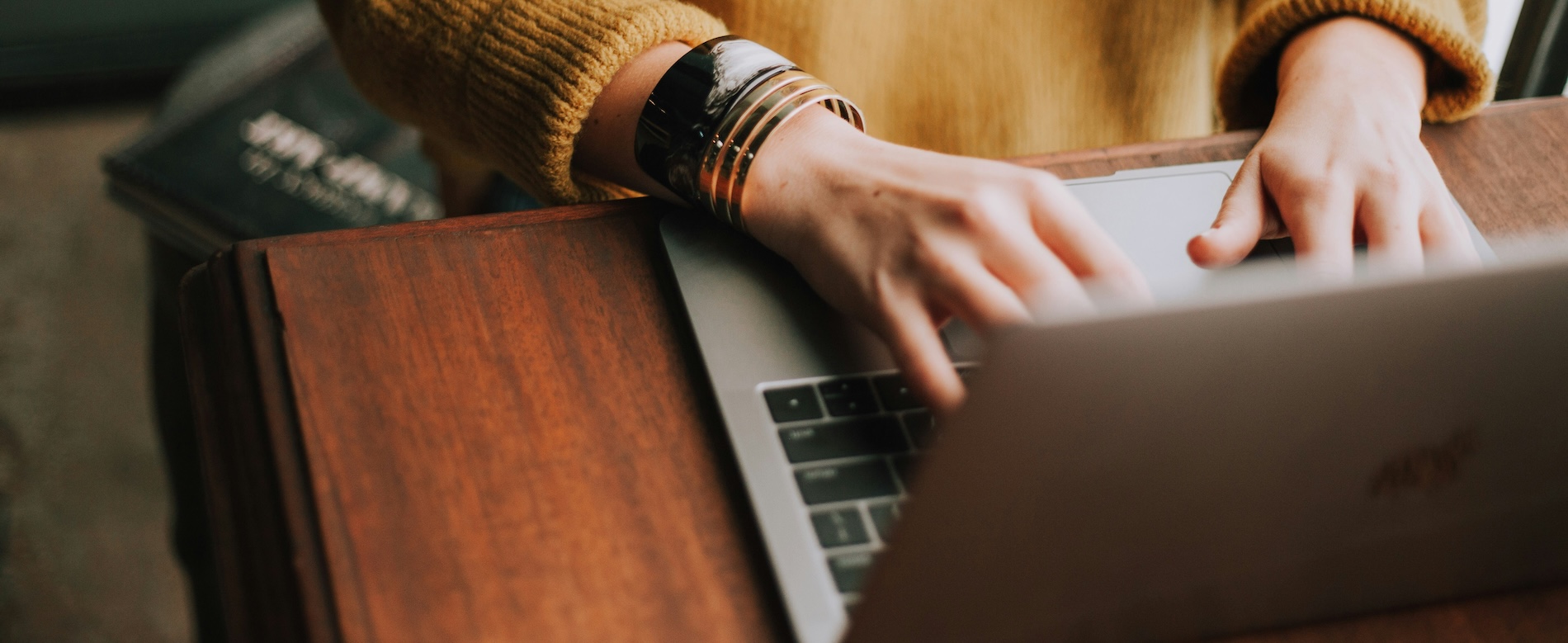 A woman's hands typing on a laptop while sitting at a desk