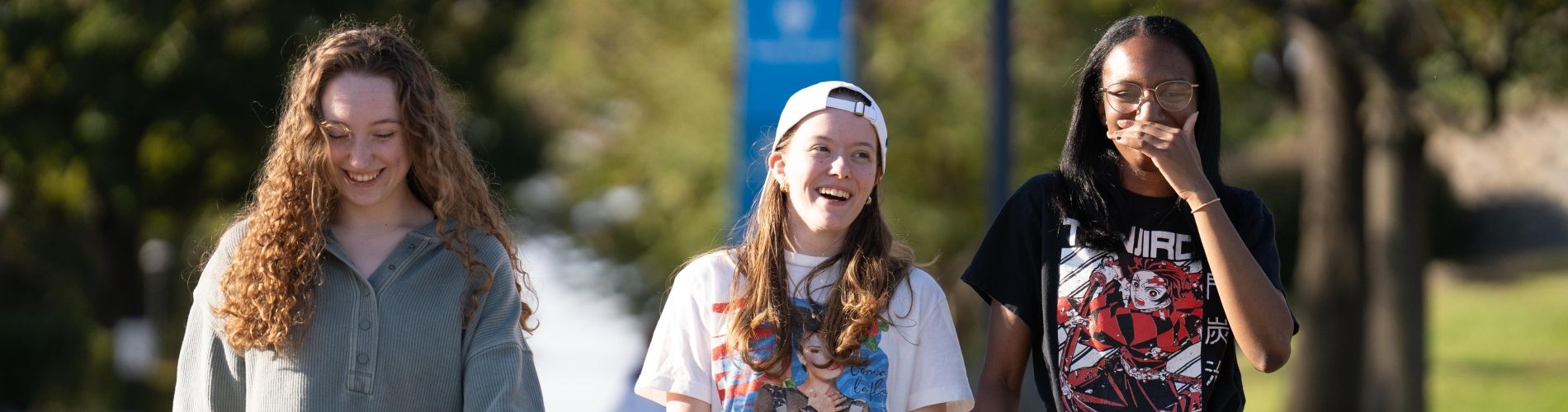 Three Holy Family students walking down a path on campus