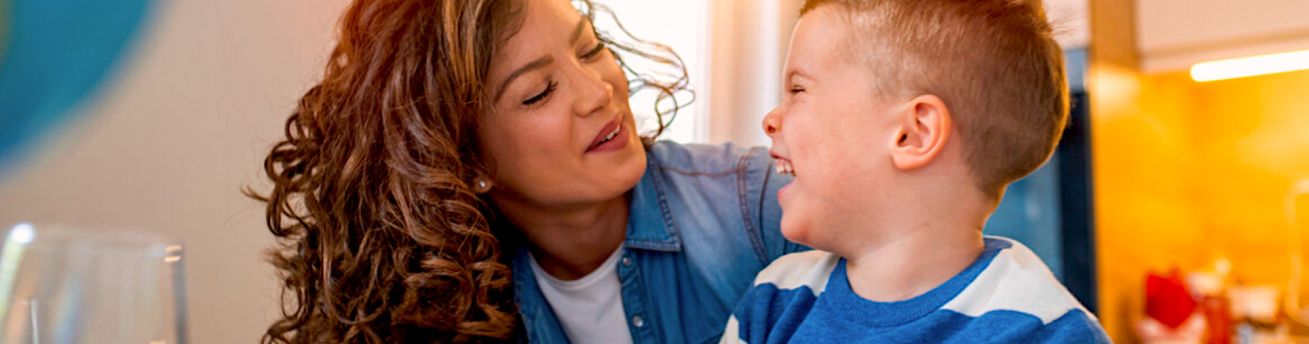 A child smiling and looking up at a caregiver in a sunny room