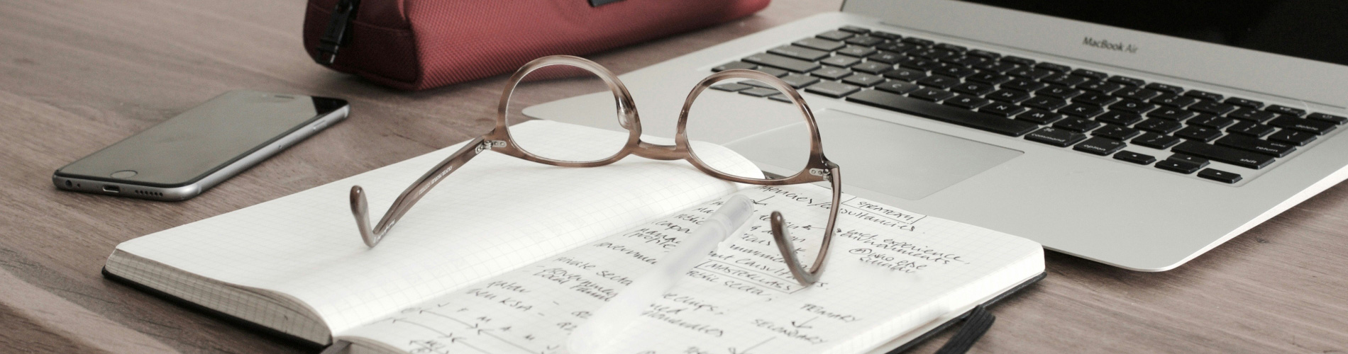 Desk with notebook, glasses and laptop