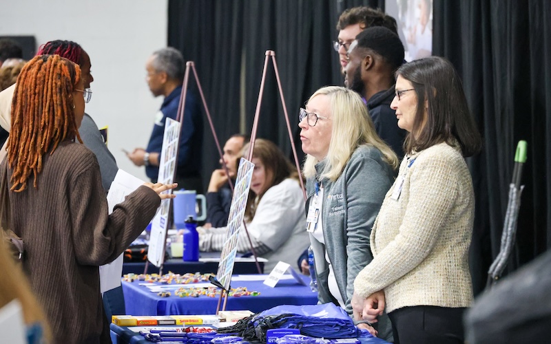 Students at a job fair speaking with employers at their booths