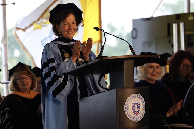 HFU President Dr. Prisco applauding the graduating class from the podium