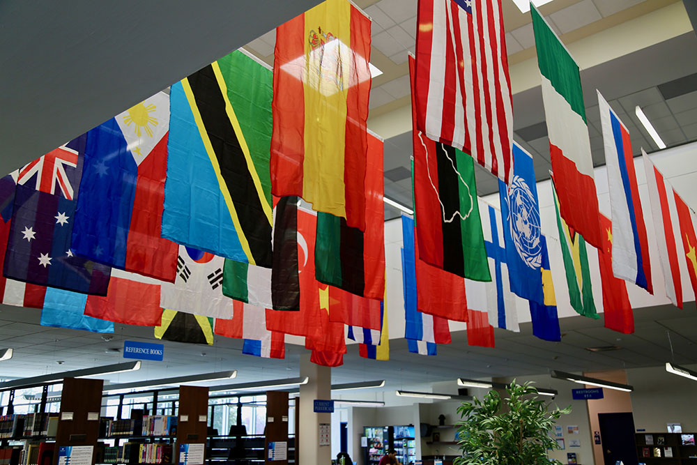 A large collection of international flags hanging from the ceiling of an HFU building