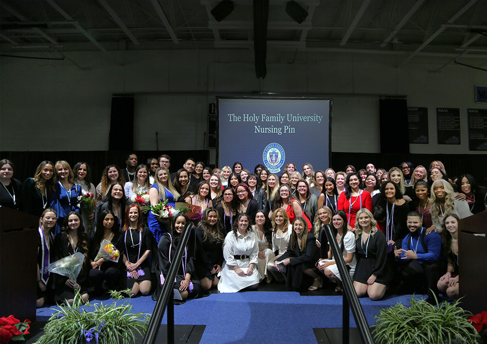 Graduating BSN students posing on stage for a class photo during the ceremony