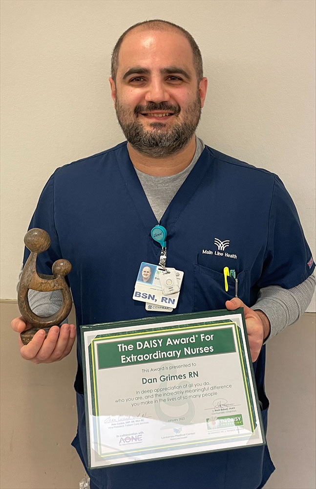 Recent alum Dan Grimes, RN '22, holding his DAISY Award for Extraordinary Nurses certificate.