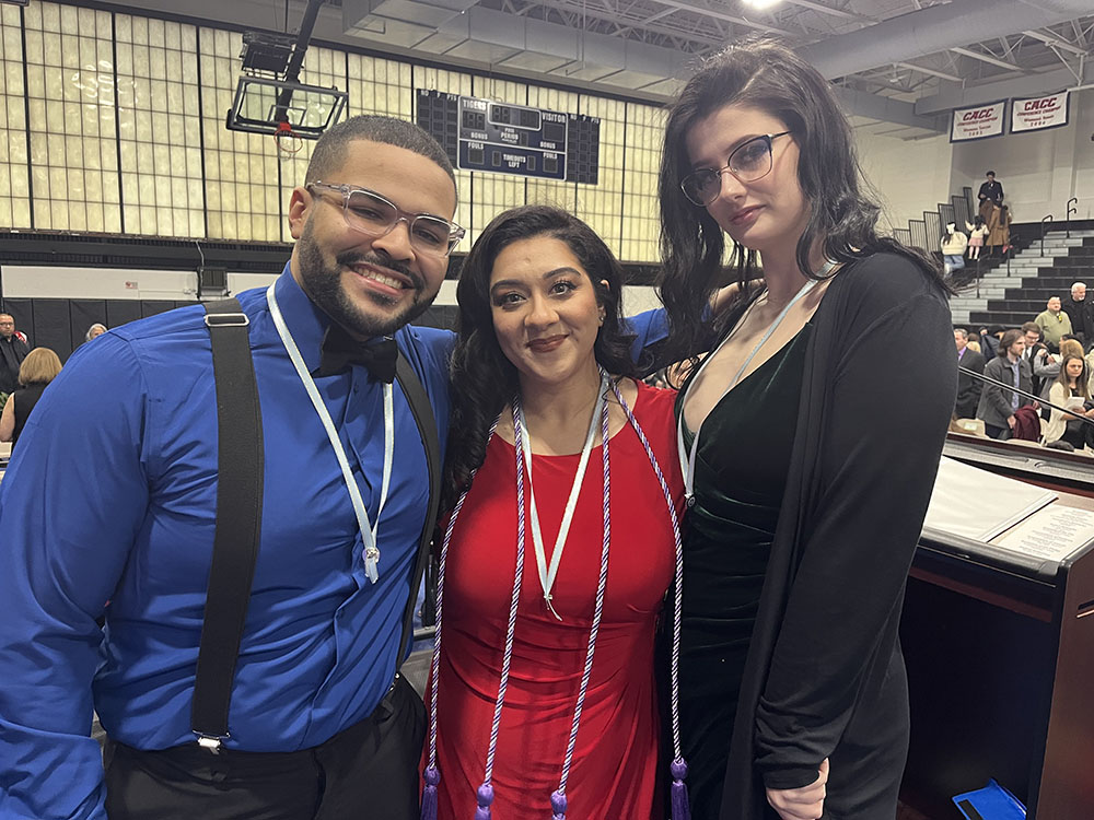 Three graduates posing with their pins