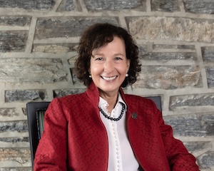 Dr. Prisco smiling and sitting in front of a stone wall