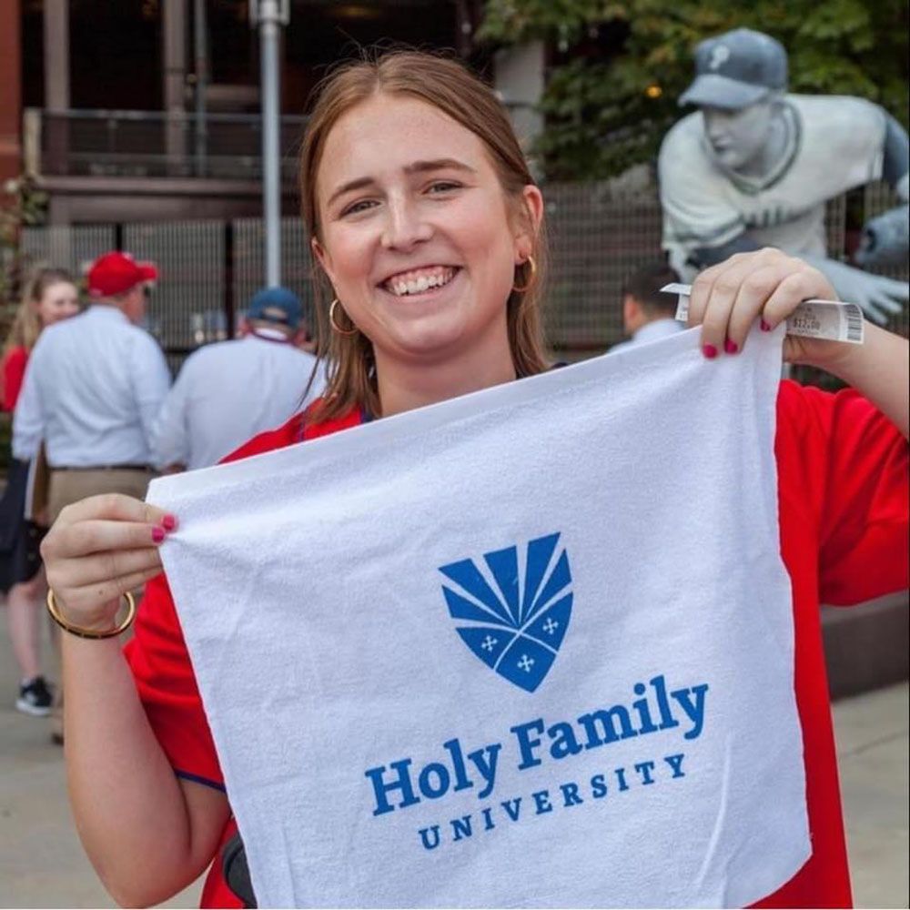 Alumni Association Board member Meghan Rakus holding Holy Family University banner