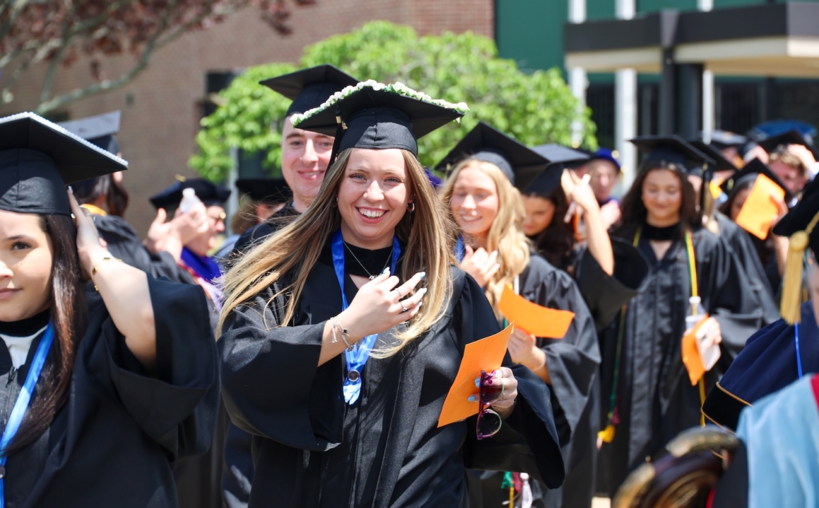 Newly graduated college students in caps and gowns processing out of their graduation ceremony