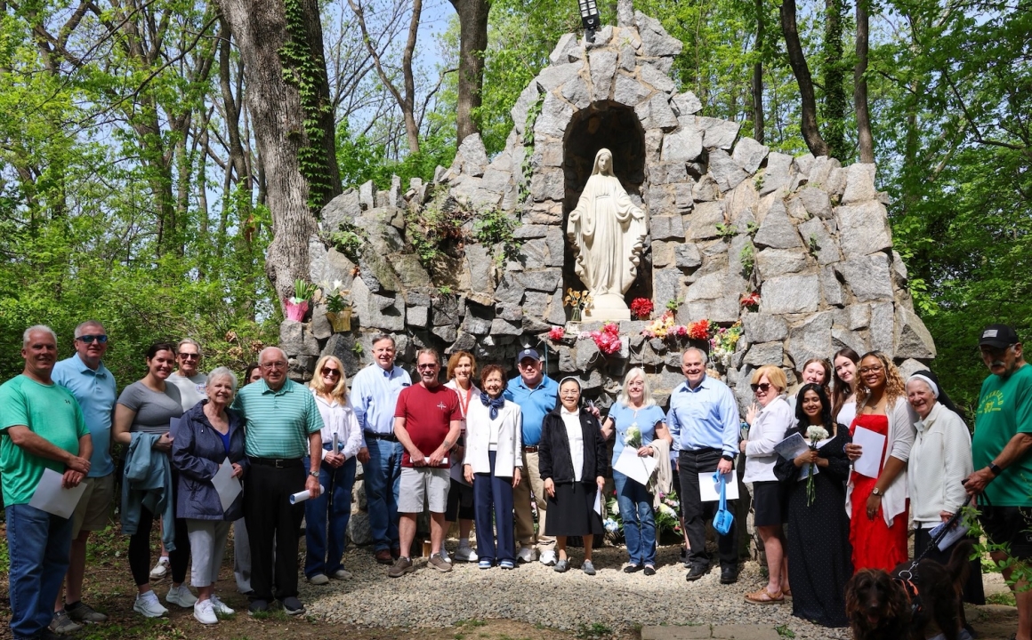 Members of the community and Holy Family gather in front of the Grotto