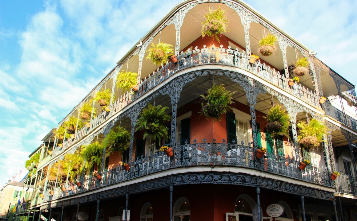 An iconic New Orleans building with hanging plants along a large balcony
