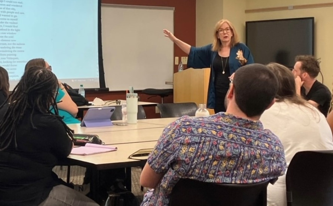 Instructor teaching creative writing class in front of classroom with group of students seated