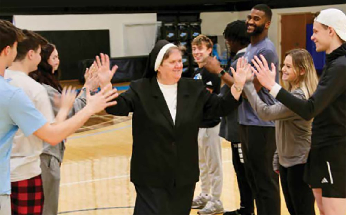 Sister Mary Joan Jacobs high fives students.