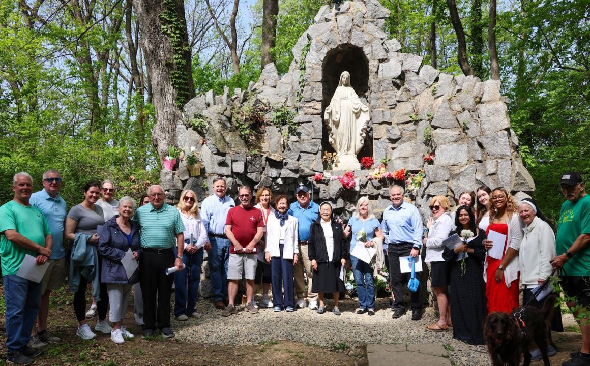 Members of the community and Holy Family gather in front of the Grotto