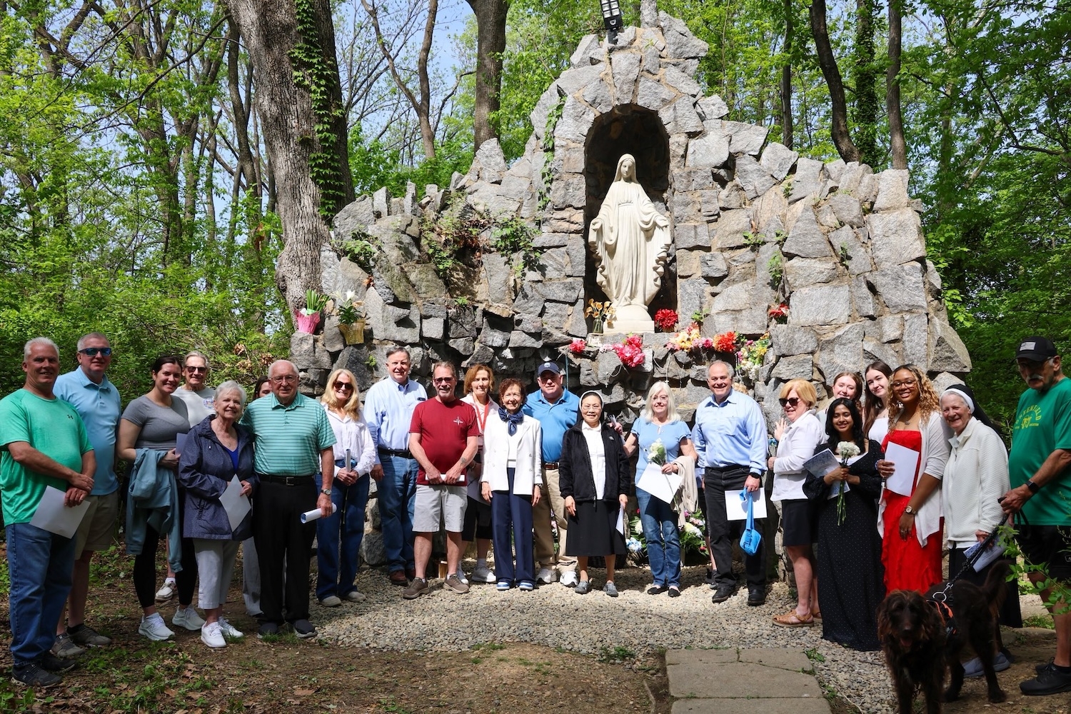 Members of the community and Holy Family gather in front of the Grotto