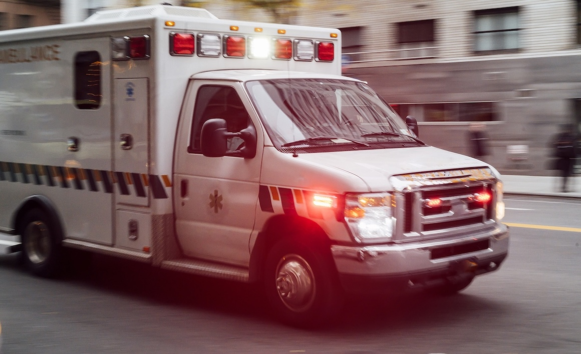 An ambulance on a city street with its lights and sirens on