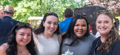 Four smiling students stand together outside of the Campus Center