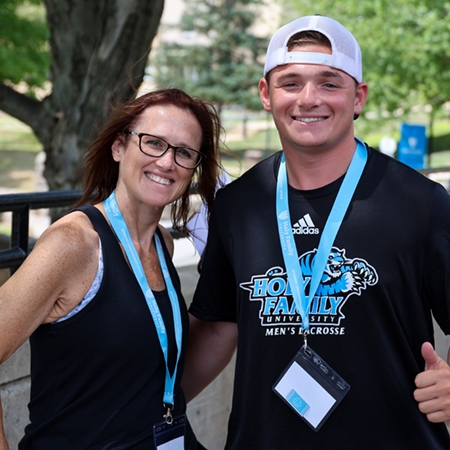 An HFU student and his mother smile while wearing Holy Family shirts