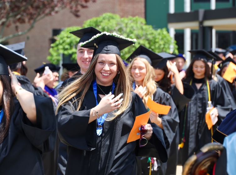 Newly graduated college students in caps and gowns processing out of their graduation ceremony