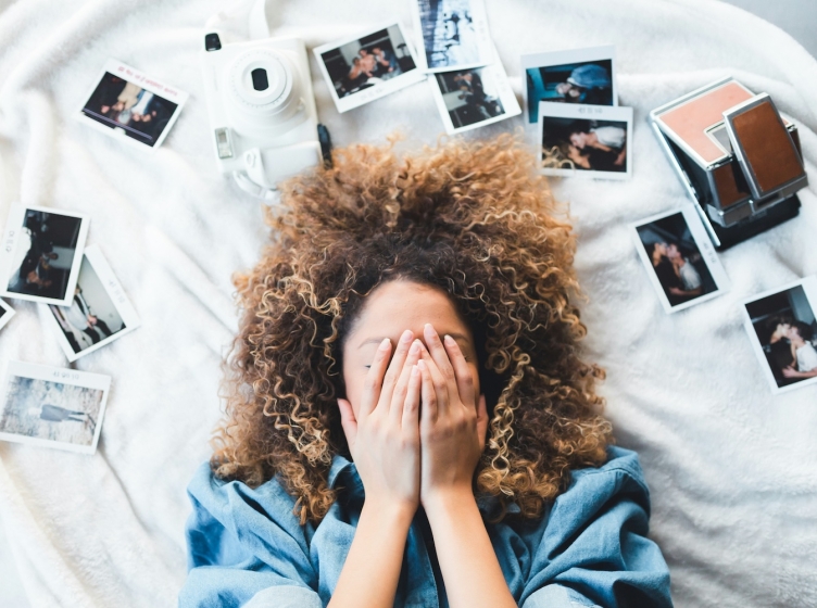 A woman laying down with her hands covering in her face in a moment of stress