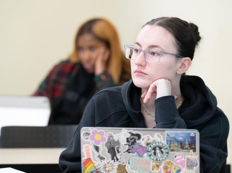 Two students in classroom with their eyes forward, listening to a professor