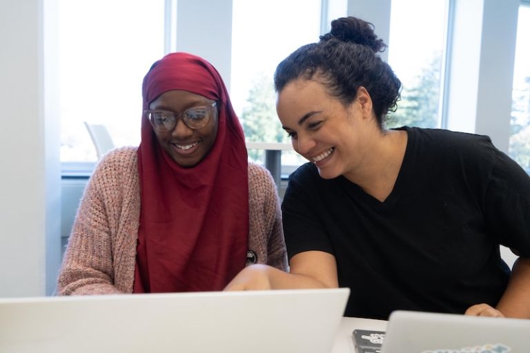 A tutor helping a student study while pointing at the student's laptop screen
